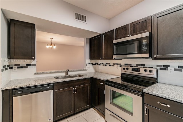 kitchen featuring sink, stainless steel appliances, tasteful backsplash, dark brown cabinetry, and light tile floors