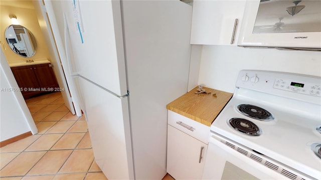 kitchen featuring white appliances, ceiling fan, light tile floors, and white cabinetry