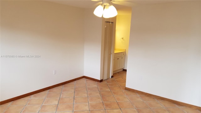 tiled empty room featuring ceiling fan