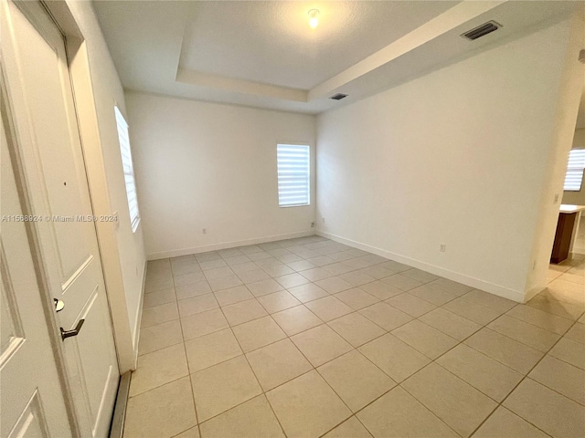 spare room with light tile floors and a tray ceiling