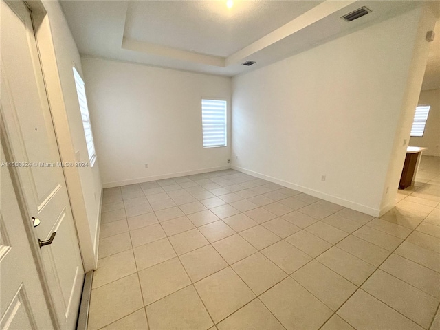 spare room featuring light tile floors and a raised ceiling