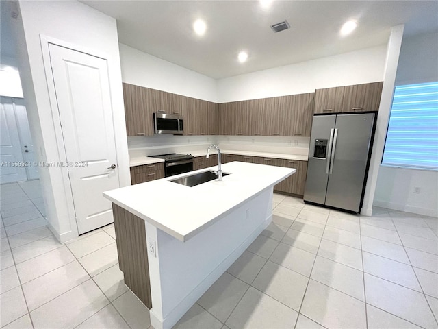 kitchen featuring appliances with stainless steel finishes, sink, a center island with sink, and light tile floors