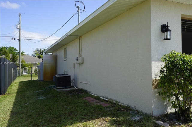 view of property exterior featuring central AC unit and a lawn