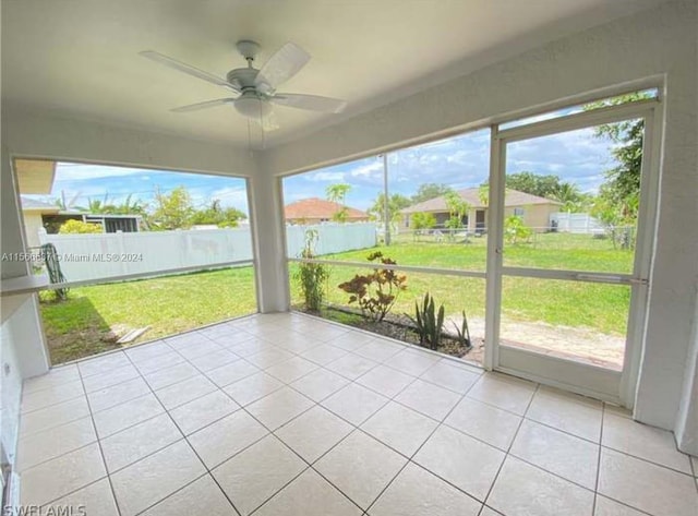 unfurnished sunroom featuring ceiling fan and a wealth of natural light