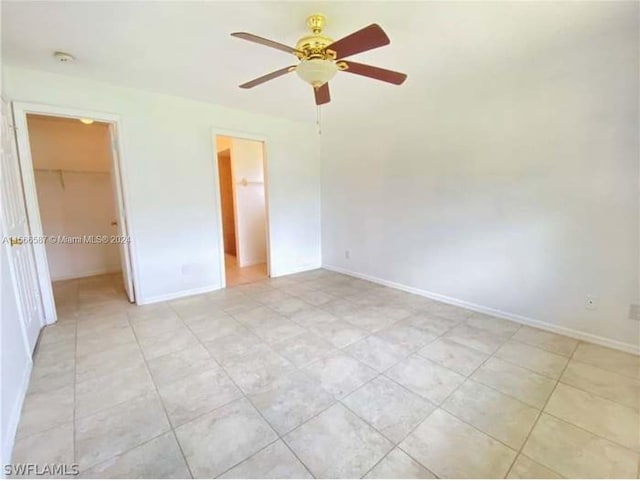 unfurnished bedroom featuring a closet, a spacious closet, ceiling fan, and light tile floors