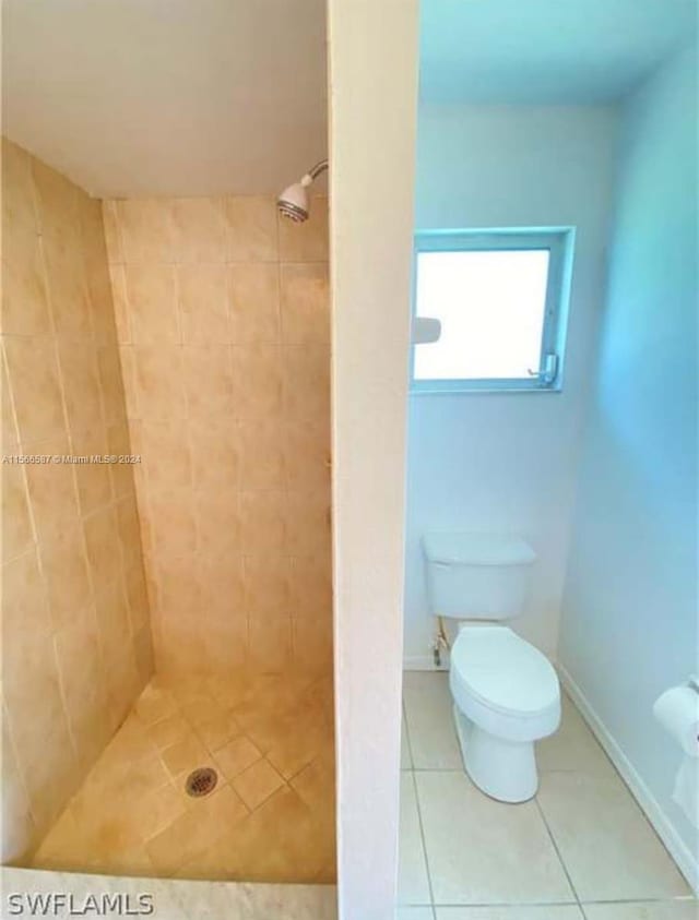 bathroom featuring tile floors, toilet, and a tile shower