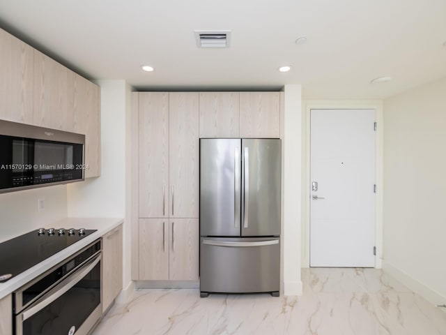 kitchen with light brown cabinetry, light tile floors, and stainless steel appliances