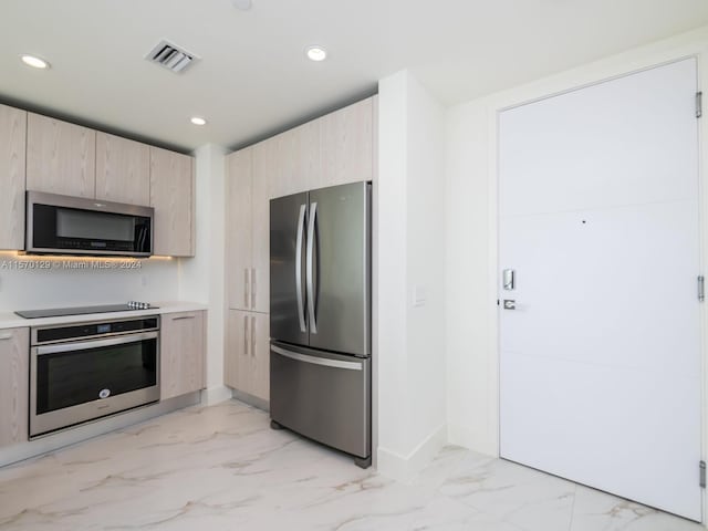 kitchen with light brown cabinets, light tile floors, and stainless steel appliances