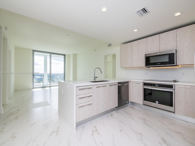 kitchen with light brown cabinetry, kitchen peninsula, stainless steel appliances, light tile floors, and sink