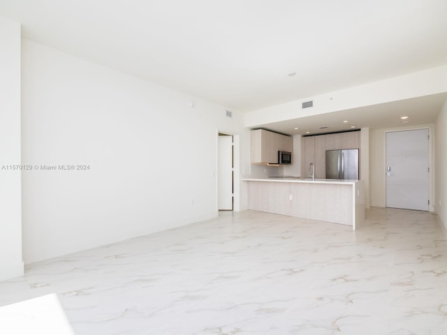 unfurnished living room featuring sink and light tile flooring