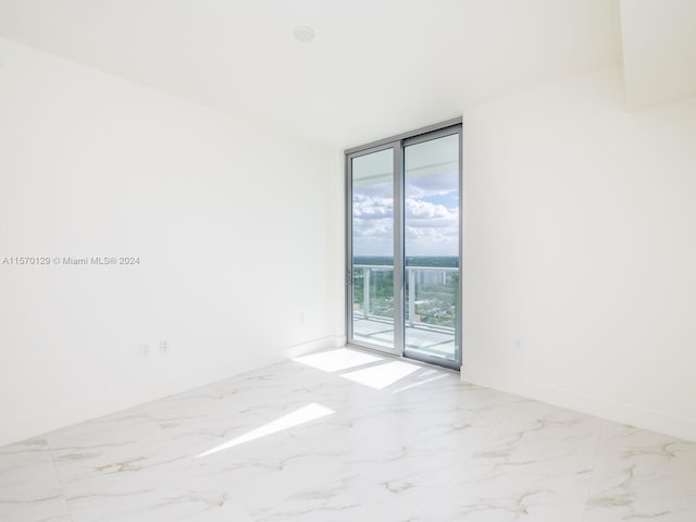 empty room featuring expansive windows and light tile flooring