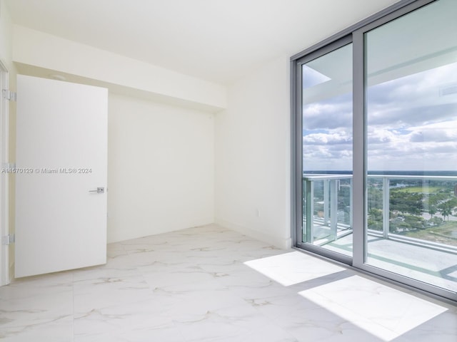 spare room with a wall of windows and light tile flooring