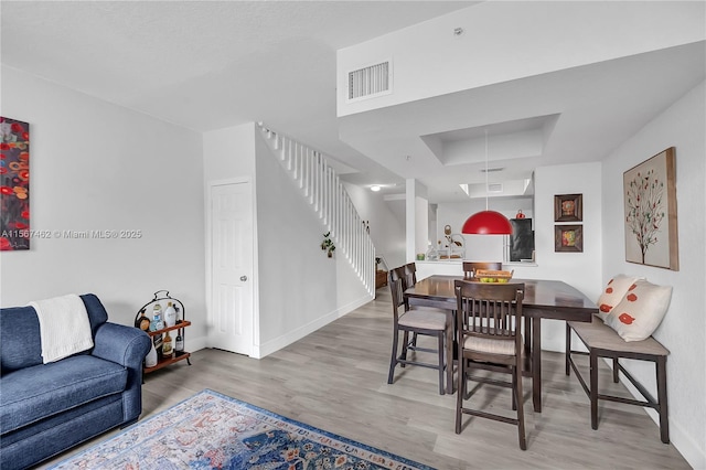 dining area featuring wood-type flooring and a tray ceiling