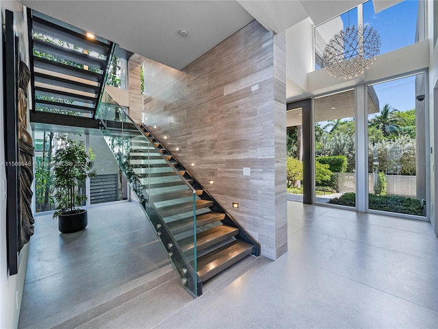 stairs with plenty of natural light, a towering ceiling, and an inviting chandelier