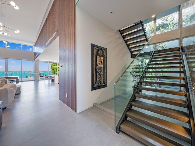 staircase featuring a high ceiling, concrete flooring, and a water view