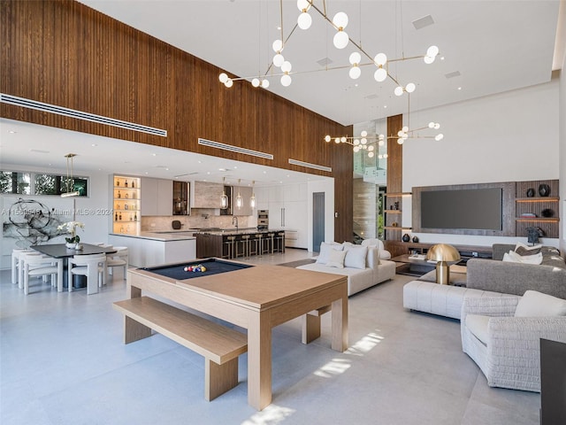 living room with a high ceiling, billiards, and a chandelier