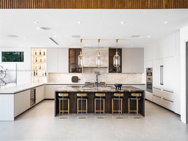 kitchen featuring a center island, double oven, backsplash, pendant lighting, and a kitchen bar