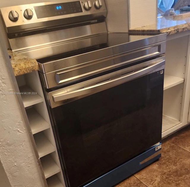 interior details with light stone countertops, dark tile patterned floors, and stainless steel electric stove