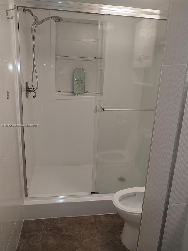 bathroom featuring tile patterned floors, a shower with door, and toilet