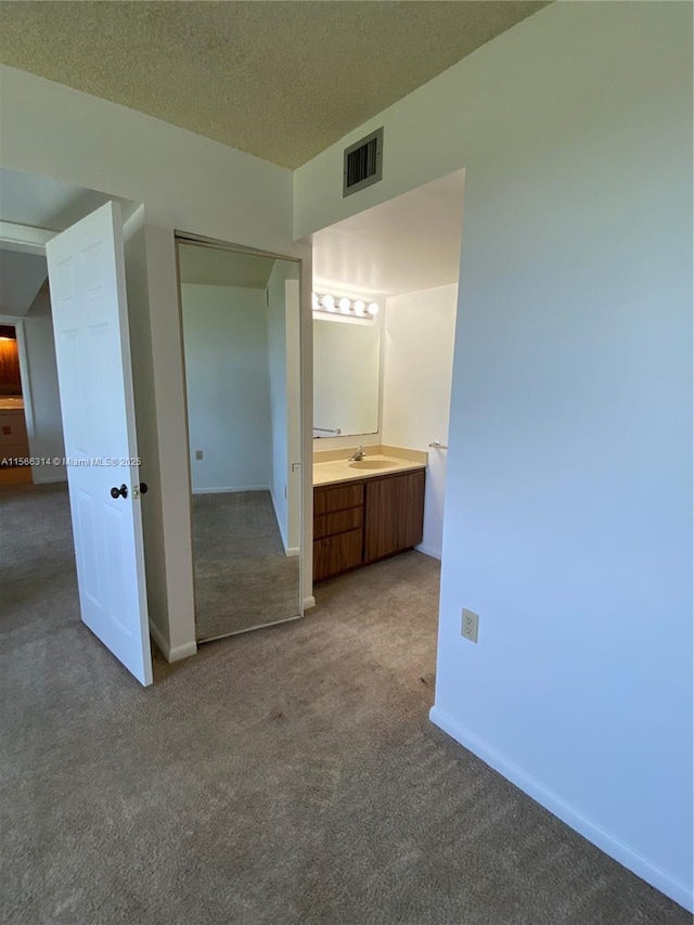 carpeted spare room with ceiling fan, baseboards, a textured ceiling, and visible vents