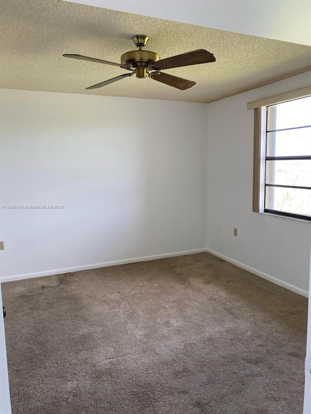 carpeted spare room with ceiling fan and a textured ceiling