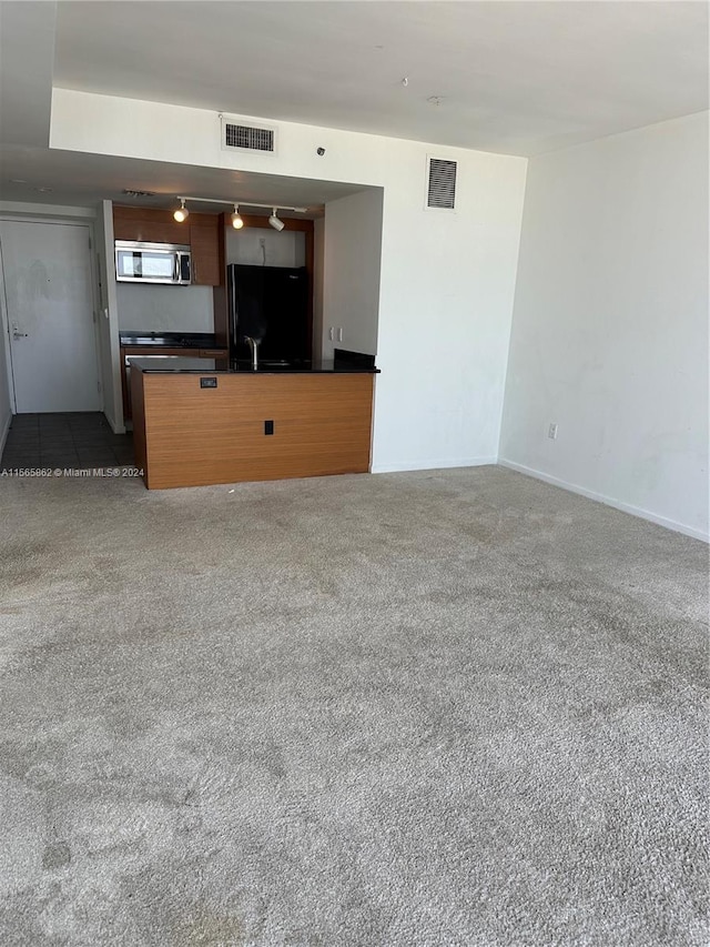 unfurnished living room with dark colored carpet