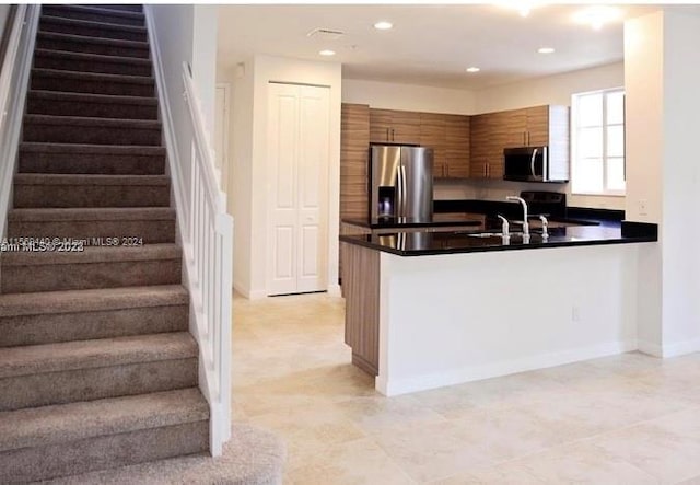 kitchen featuring stainless steel appliances, sink, light tile floors, and kitchen peninsula