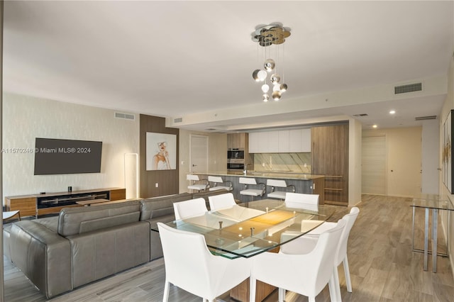 dining space featuring light hardwood / wood-style floors and an inviting chandelier