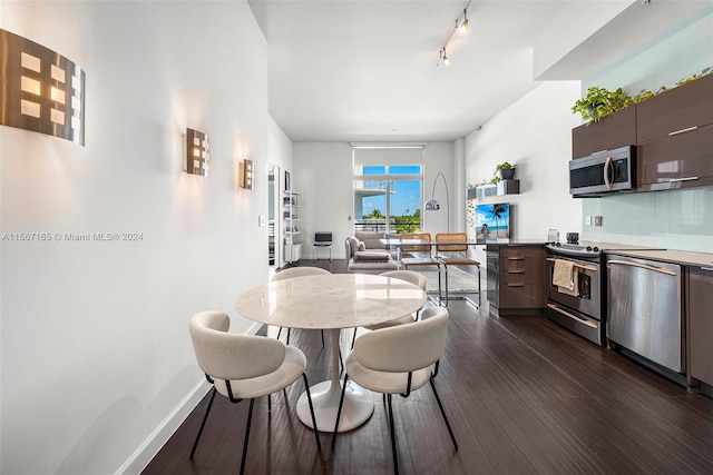 dining area featuring track lighting and dark wood-type flooring