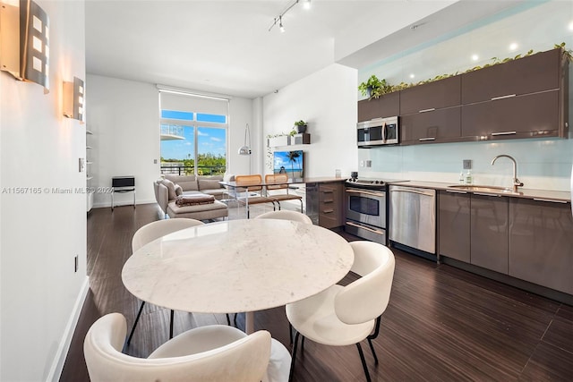 dining area featuring track lighting, dark hardwood / wood-style flooring, and sink