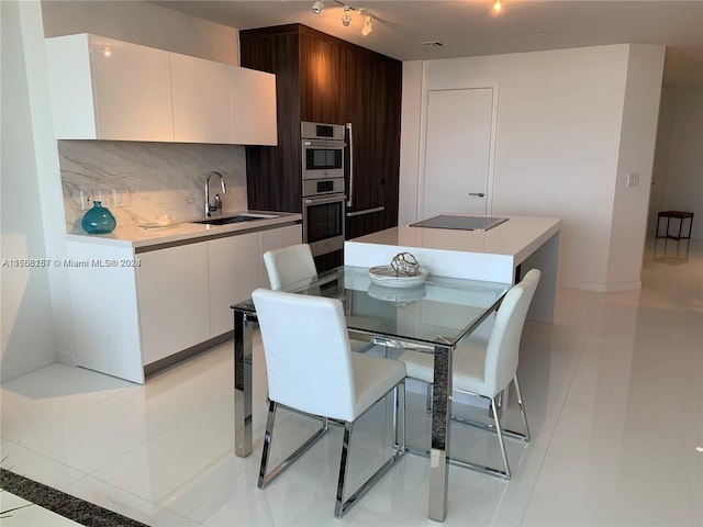 kitchen featuring white cabinets, tasteful backsplash, light tile patterned flooring, and sink