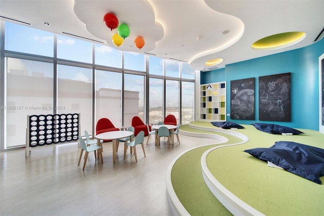 bedroom with a tray ceiling, hardwood / wood-style flooring, and a wall of windows