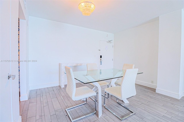 dining area with light hardwood / wood-style floors and a chandelier