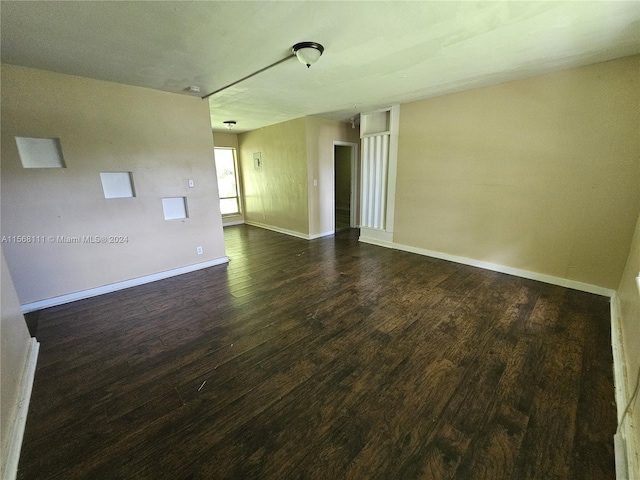 unfurnished room featuring dark wood-style floors and baseboards