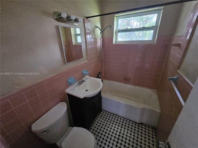 full bath with shower / tub combination, toilet, a wainscoted wall, vanity, and tile walls