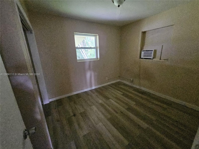 spare room featuring cooling unit, baseboards, and wood finished floors