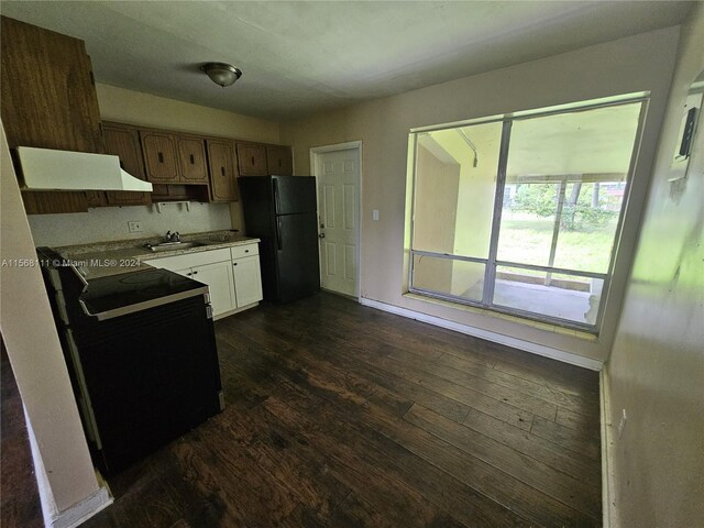 kitchen with dark wood-type flooring, freestanding refrigerator, light countertops, a sink, and range with electric stovetop