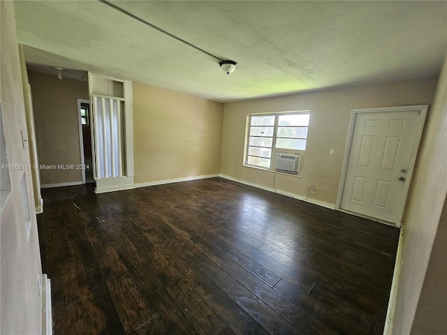 spare room featuring dark wood-type flooring, cooling unit, and baseboards