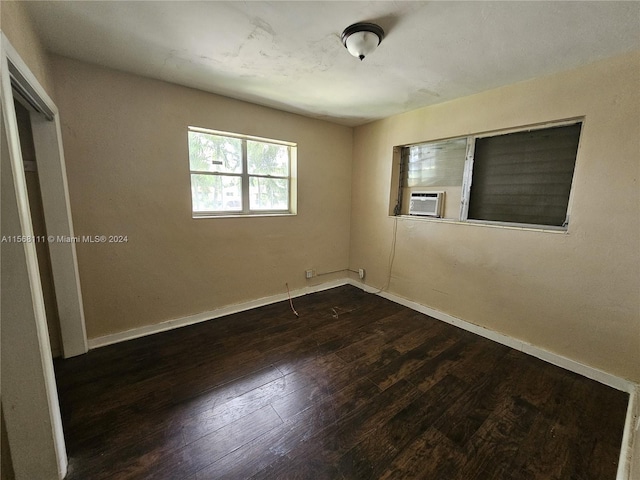 spare room featuring cooling unit, dark wood-style flooring, and baseboards