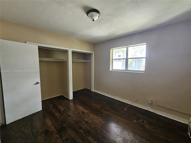 unfurnished bedroom with dark wood-type flooring and a closet