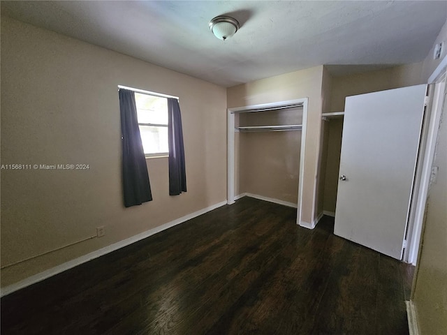 unfurnished bedroom with a closet, wood finished floors, and baseboards