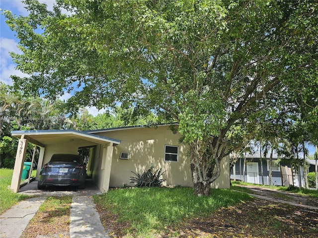 view of front of property with a carport, a front yard, driveway, and stucco siding