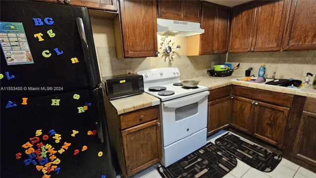 kitchen with tile counters, light tile flooring, black appliances, backsplash, and sink