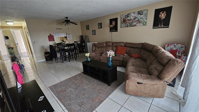 living room featuring ceiling fan, light tile flooring, and a textured ceiling