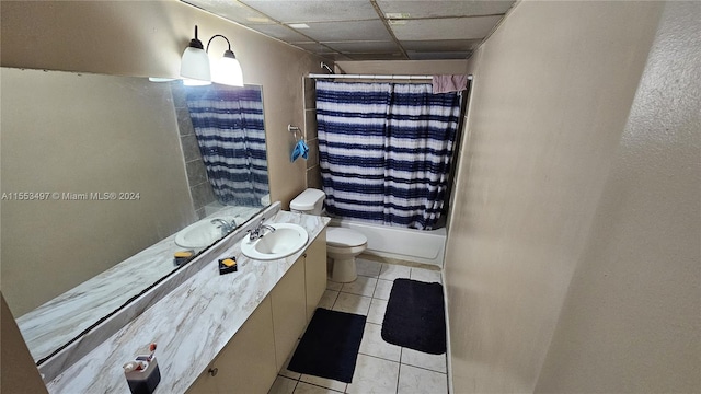 full bathroom with tile floors, vanity, shower / tub combo with curtain, a drop ceiling, and toilet