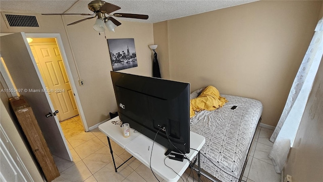 bedroom featuring ceiling fan, light tile flooring, and a textured ceiling