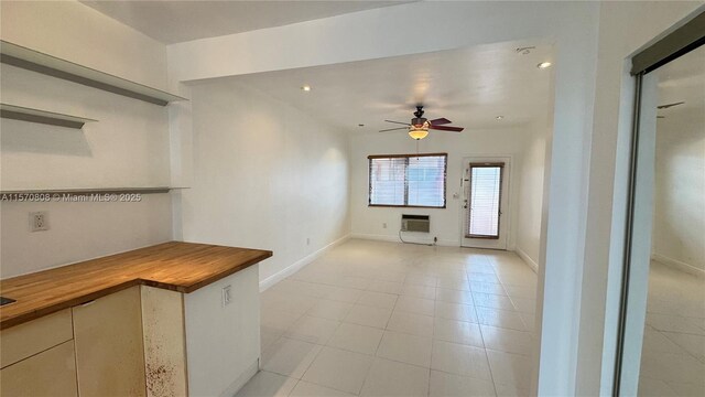 interior space with electric panel, sink, butcher block counters, light tile patterned floors, and dishwasher