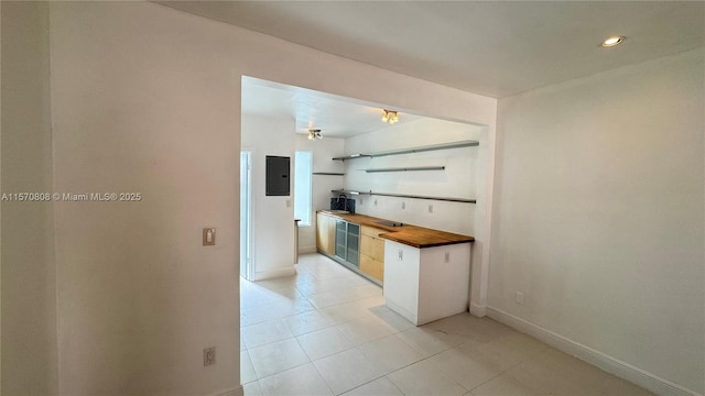 kitchen with electric panel, light tile patterned floors, and butcher block counters