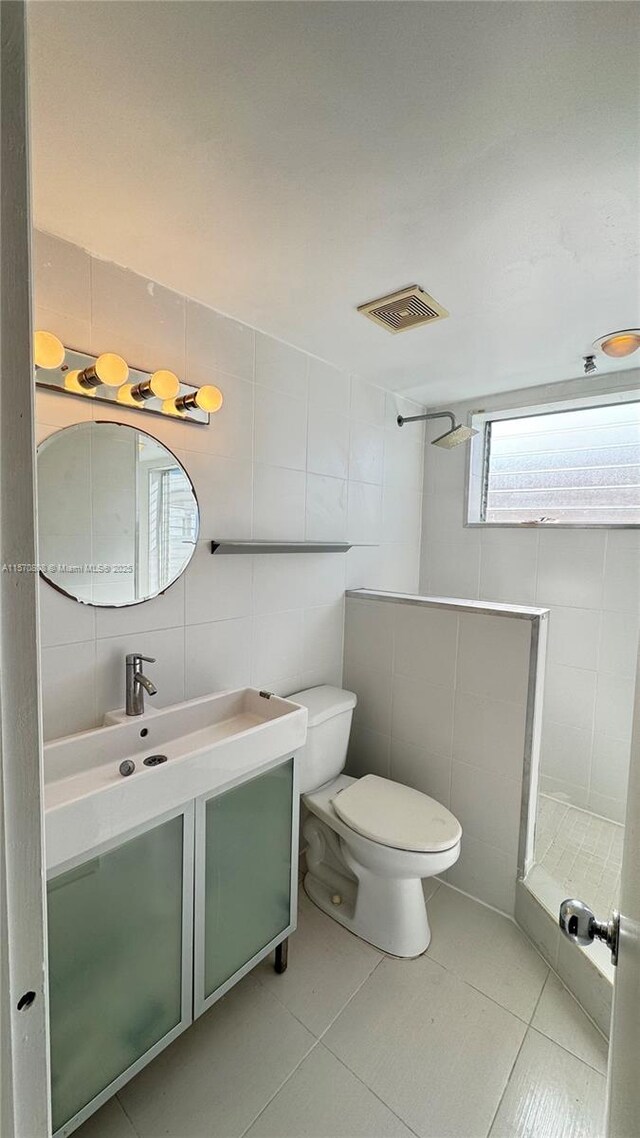 bathroom featuring tile patterned floors, toilet, tile walls, backsplash, and vanity