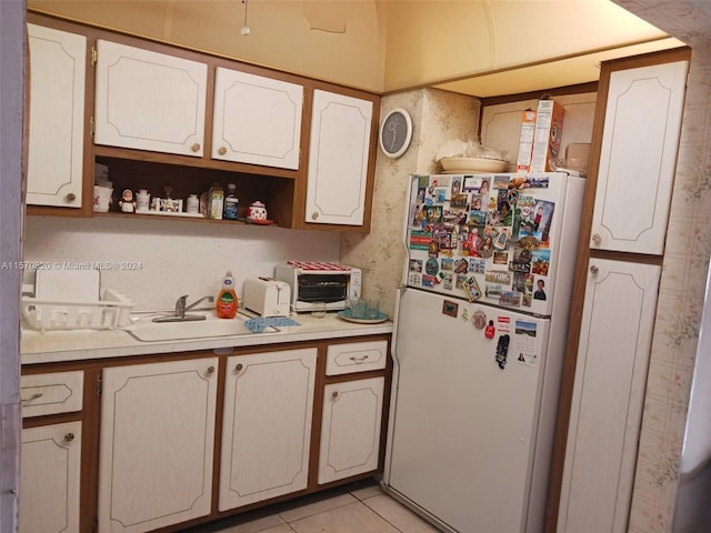 kitchen featuring sink, white fridge, white cabinetry, and light tile floors